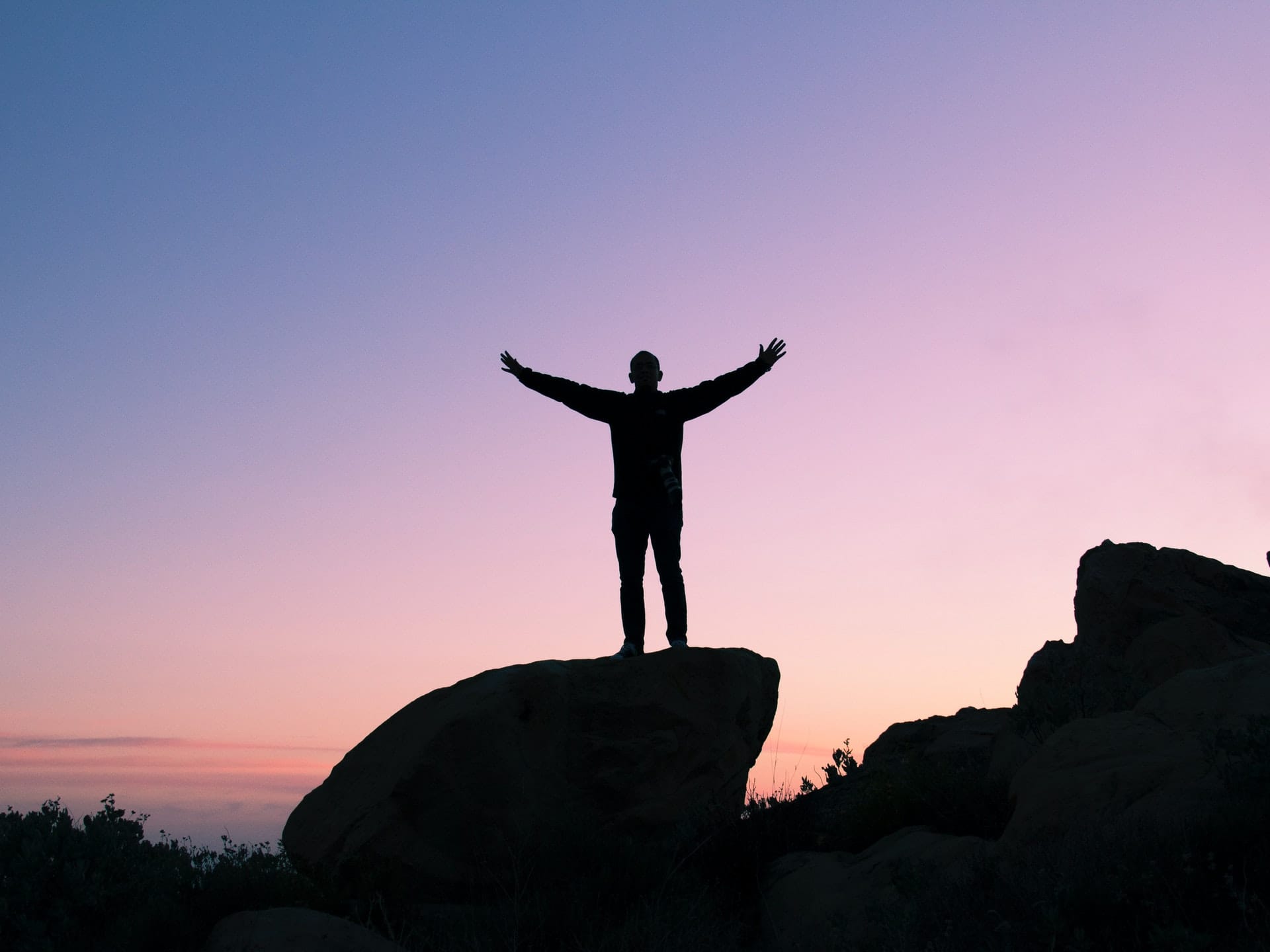 man raising his arms to the sky to express tranquility