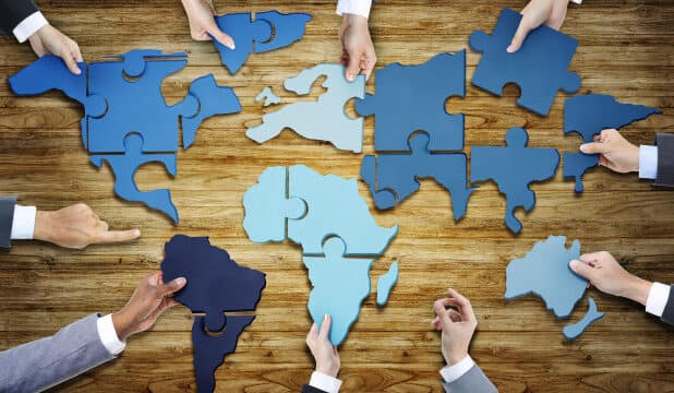 group of business people with jigsaw puzzle forming in world map